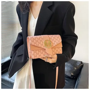Detailed view of pink crossbody bag with M-pattern print and gold metallic buckle
