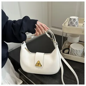 Close-up of white leather half-moon bag featuring a gold-tone triangle buckle