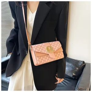 Pink crossbody bag with embossed M pattern and gold metal buckle worn by a model