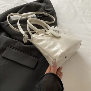 Détail du sac en cuir brillant blanc avec nœud en dentelle et clous de protection argentés