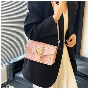 Detail of pink crossbody bag with embossed M pattern and gold circular metal buckle