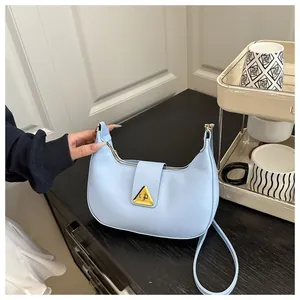 Detail showing smooth light blue leather and gold triangular buckle on hobo bag