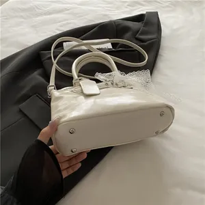 Détail d'un sac à main en cuir PU crème avec boucles argentées et ruban en dentelle