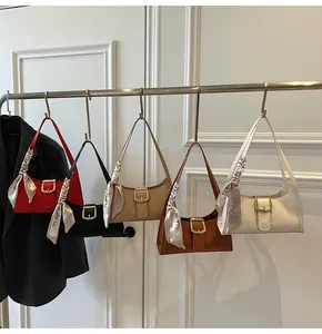 Dettaglio di eleganti borse a spalla in cinque colori con foulard e fibbie dorate
