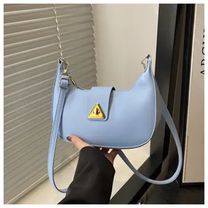 Detailed view of light blue crescent bag featuring a golden triangle metal clasp and PU leather