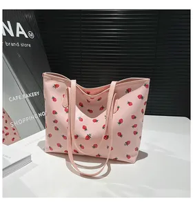 Gros plan du sac cabas en similicuir rose avec motifs d'imprimés de fraises rouges