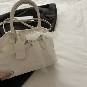 Détail du sac à bandoulière crème en similicuir avec nœud en dentelle et sangle ajustable