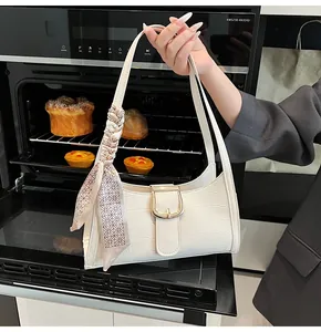 Dettaglio borsa bianca motivo coccodrillo con fibbia dorata e decorazione in seta