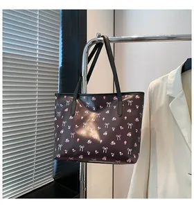 Détail d'un sac cabas floral avec nœuds roses suspendu à un cintre en métal sous la lumière