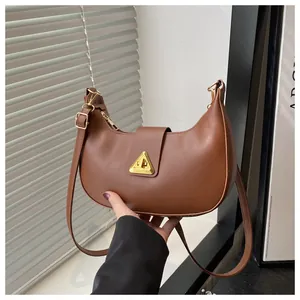 Close-up of brown crescent underarm bag with gold triangle lock and adjustable strap