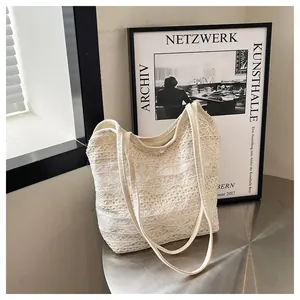 Detailaufnahme der weißen Spitzen-Tote-Bag mit floralem Häkelmuster auf Metalltisch