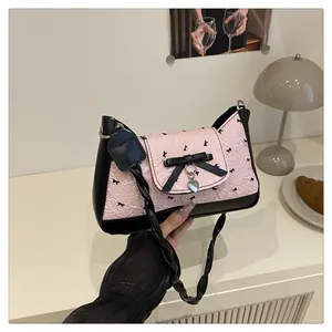 Détail du sac plissé rose orné de nœuds noirs et d'un pendentif en forme de cœur