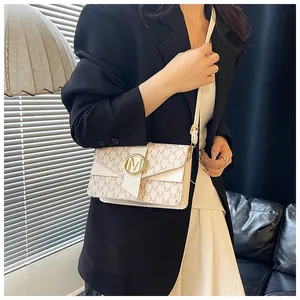 Close-up of off-white crossbody bag with M-pattern print and metallic ring lock on a model