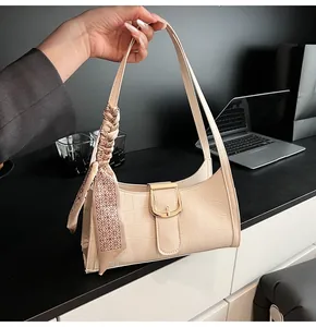 Dettaglio borsa a spalla crema effetto coccodrillo con fibbia dorata e foulard di seta
