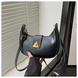 Detail of the black leather crescent bag showing the gold triangular metal clasp closure