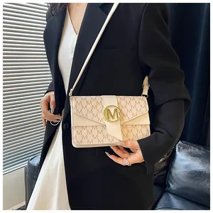 Detail of crossbody bag featuring beige leather and brown letter M monogram pattern