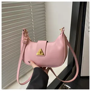 Detailed close-up of pink crescent underarm bag with gold triangle lock buckle
