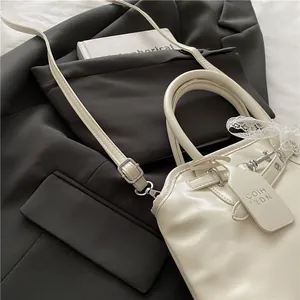 Détail du sac crème en similicuir avec nœud en dentelle et poignée ronde sur un veston