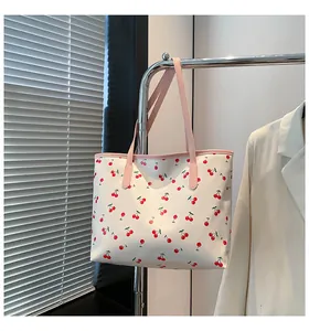 Vue détaillée du sac cabas à imprimé cerise avec anses roses près d'un blazer blanc