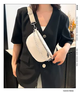 Détail du sac ceinture beige en demi-lune avec chaîne argentée et large bandoulière