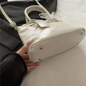 Détail d'un sac à main en cuir crème avec rivets de protection et décor en dentelle