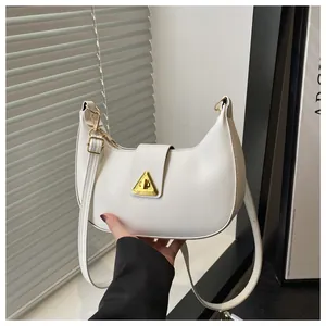 Detail of white hobo bag showing gold triangle clasp and smooth faux leather texture