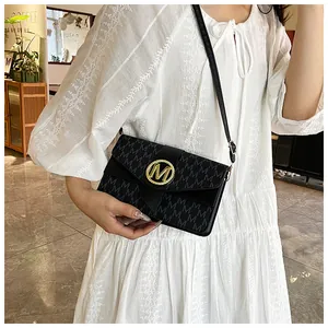 Detail of black crossbody bag featuring gold M logo and repeating monogram pattern