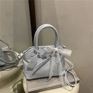 Gros plan d'un sac en cuir bleu clair avec nœud en dentelle et breloque logo