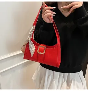 Dettaglio della borsa rossa a motivo coccodrillo con fibbia dorata e foulard di seta