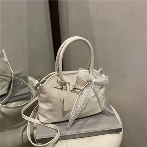 Détail du sac bandoulière blanc cassé avec nœud en dentelle et étiquette en cuir