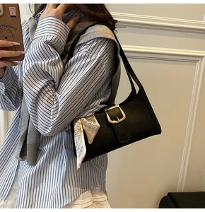 Dettaglio borsa a spalla con trama coccodrillo, fibbia dorata e foulard in seta