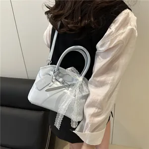 Détail du sac à main bleu clair brillant avec nœud en dentelle blanche et bandoulière