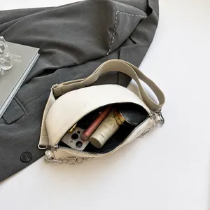 Detail showing the internal storage capacity of the beige half-moon crossbody bag
