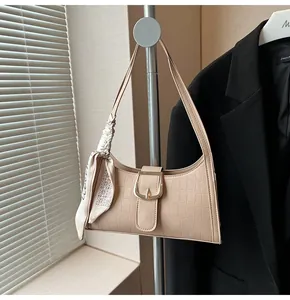 Dettaglio della borsa baguette beige con motivo coccodrillo, fibbia dorata e foulard in seta