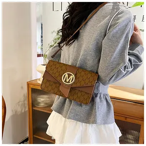 Close-up of brown crossbody bag with letter print and gold M-shaped metal buckle