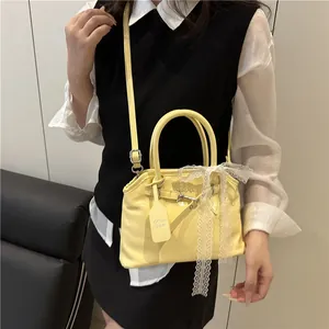 Détail d'un sac à main en cuir verni jaune avec nœud en dentelle et bandoulière