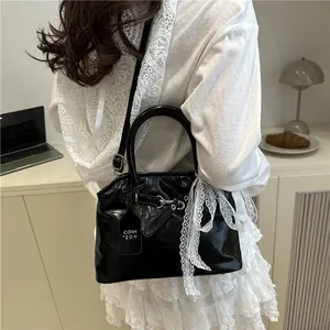 Détail d'un sac à main en cuir verni noir avec ruban de dentelle blanche et anses
