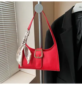 Dettaglio della borsa a spalla rossa con goffratura coccodrillo, fibbia oro e foulard