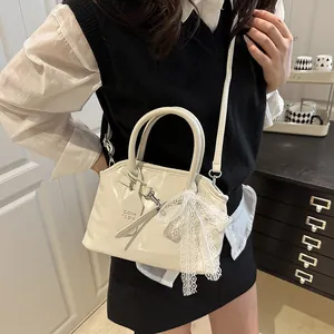 Gros plan d'un sac à main en cuir verni blanc crème avec un nœud en dentelle délicat
