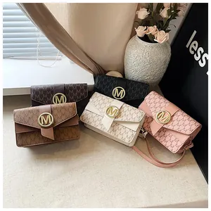 Flat lay of small crossbody bags in five colors with M-pattern and gold metal logos