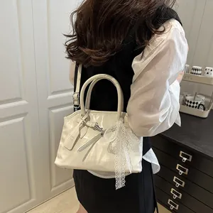 Vue détaillée du sac bandoulière en cuir crème avec nœud en dentelle et sangle