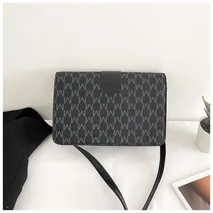 Detail of black crossbody bag featuring grey M letter print and leather flap closure