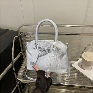 Sac à main en similicuir bleu clair orné d'un grand nœud en dentelle blanche et forme coquille