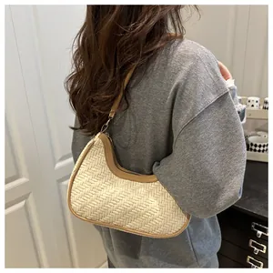 Dettaglio di una borsa a mezzaluna intrecciata crema con tracolla in pelle marrone su modella