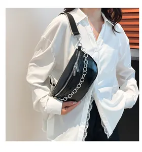 Detail view of black half-moon waist bag featuring silver chain and wide woven strap