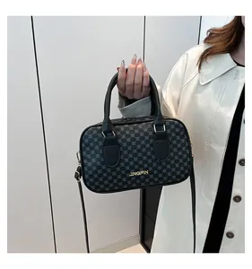 Détail du sac Boston montrant le logo en métal doré et le motif géométrique noir