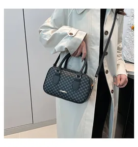 Détail du sac Boston gris avec imprimé géométrique et logo doré sur trench beige