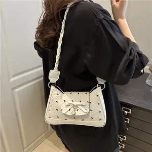 White French-style baguette bag featuring black bow patterns and silver heart charm
