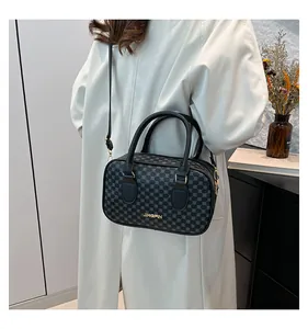 Détail du sac Boston avec motifs gris géométriques et logo doré sur cuir noir élégant