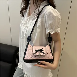 Pink bow underarm bag with black trim, heart pendant, and woven shoulder strap